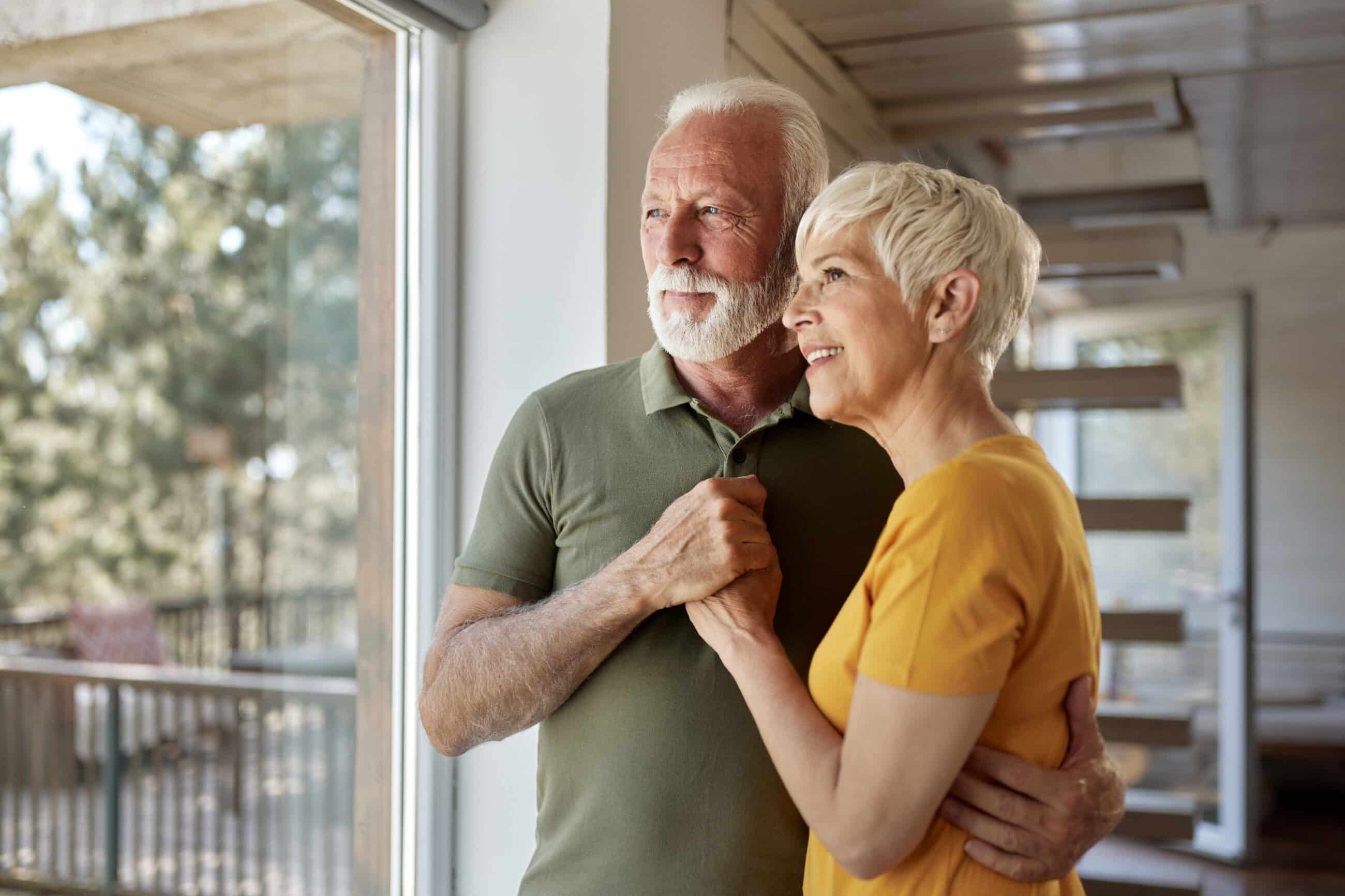 Happy mature couple looking out of window scaled