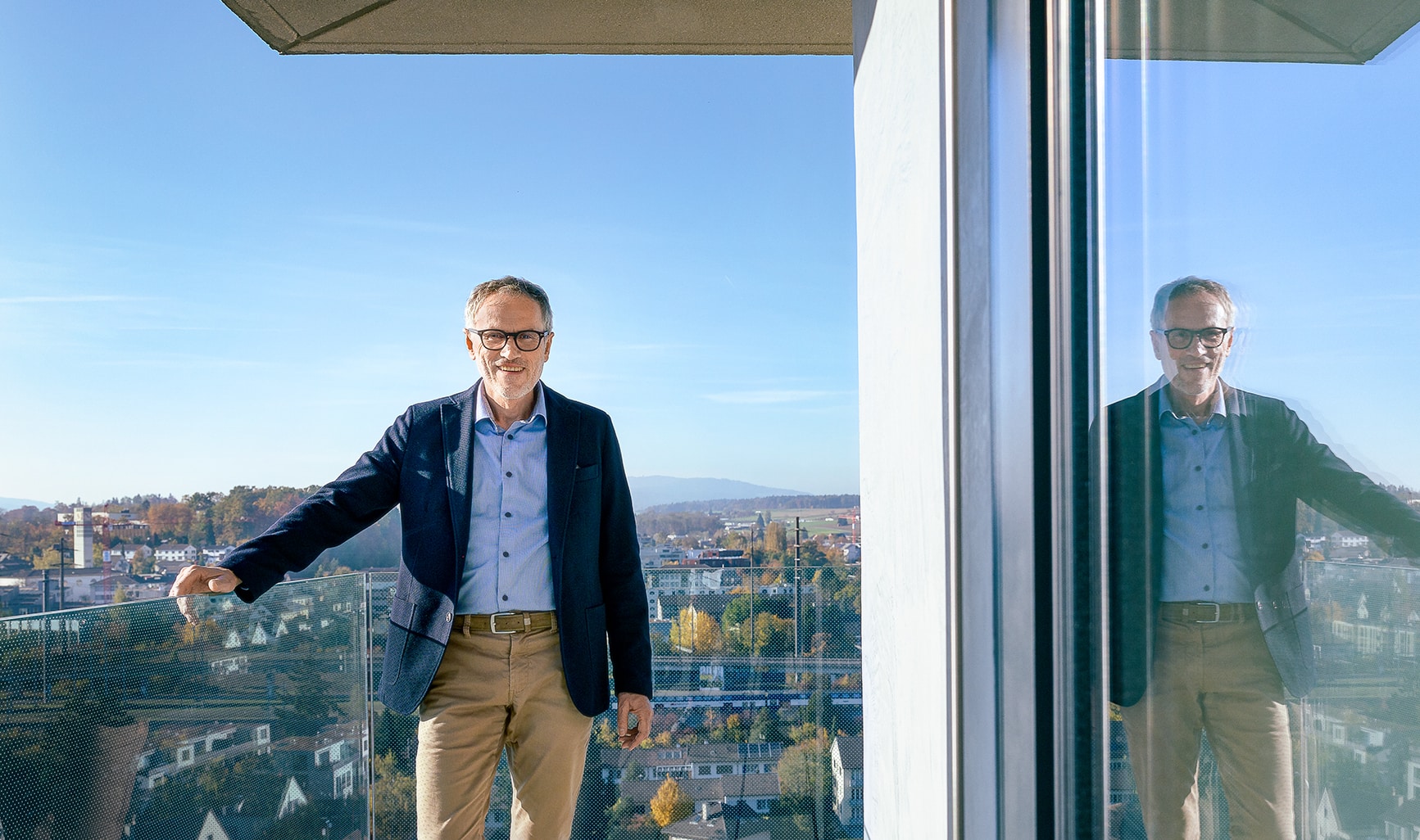 Porträt von Stefan Schmid, der lächelnd in einem urbanen Umfeld steht.