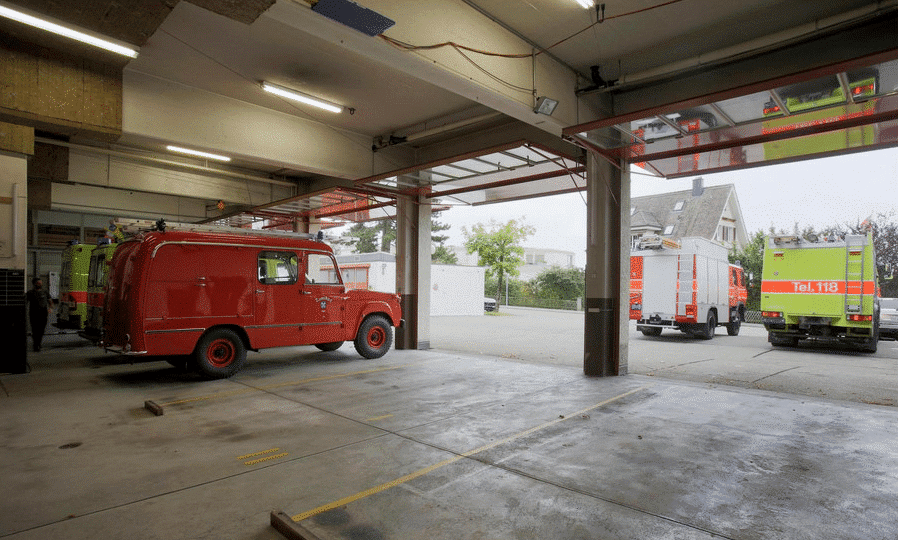 Schwarze Teekanne auf einem Holztisch mit frischen Kräutern und Teetassen