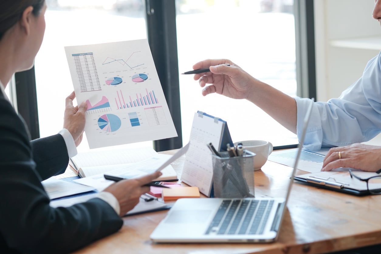 Blick auf eine malerische Landschaft mit grünen Wiesen und bewaldeten Hügeln unter einem klaren Himmel.