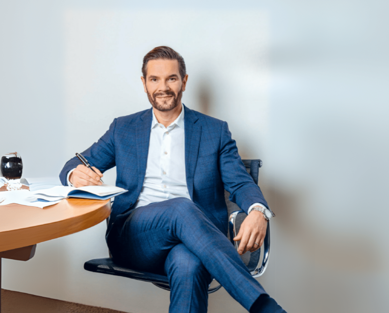Raphael Fischer, Neubau-Experte bei Ginesta Immobilien, lächelt vor einem modernen Gebäude.
