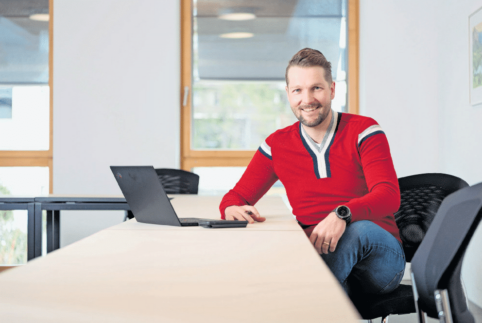 Porträt von Sascha mit einem lächelnden Gesicht in einem modernen Büro