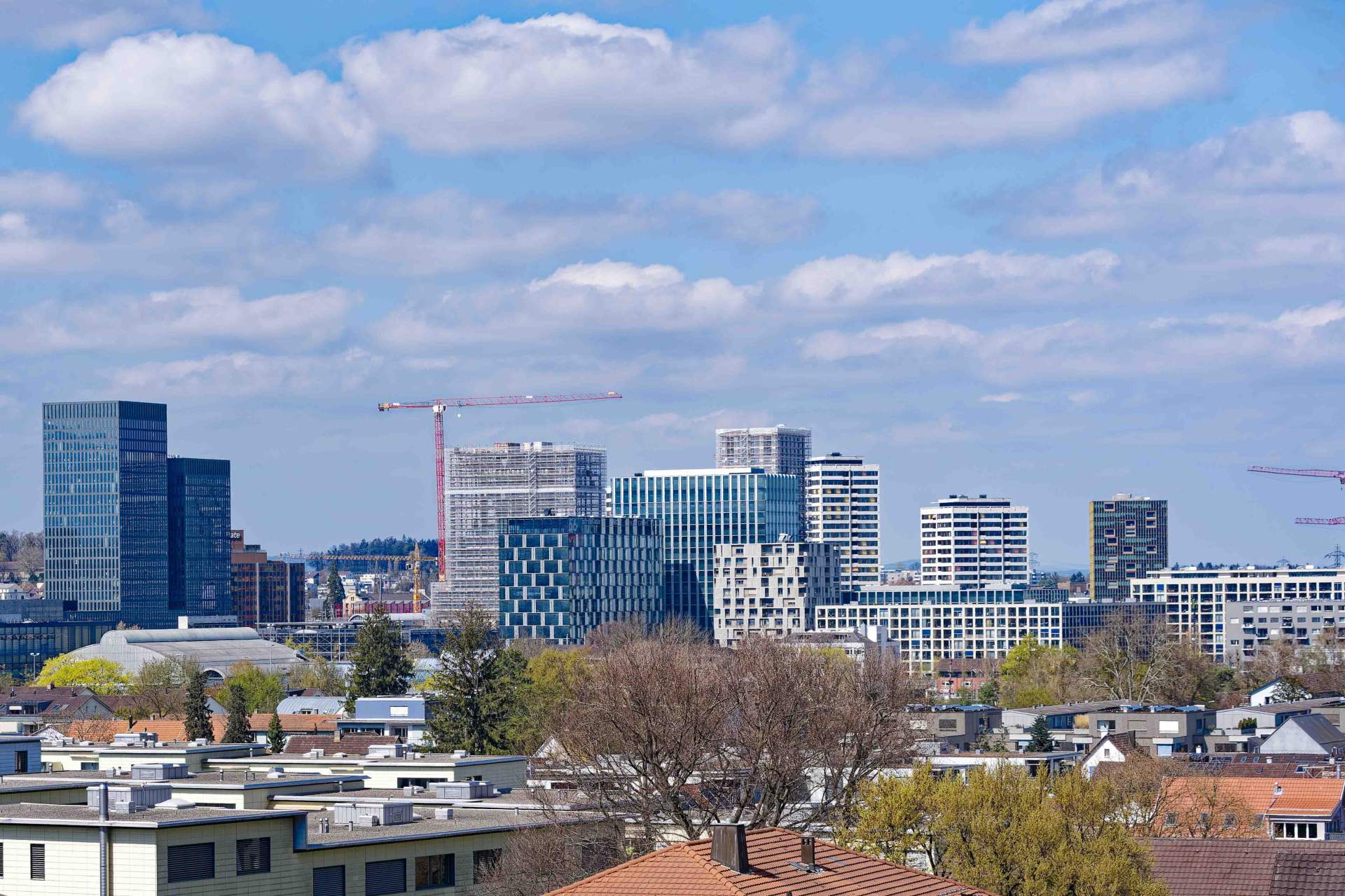 Schweizer Skyline von Zürich Nord mit Baukran im Vordergrund.
