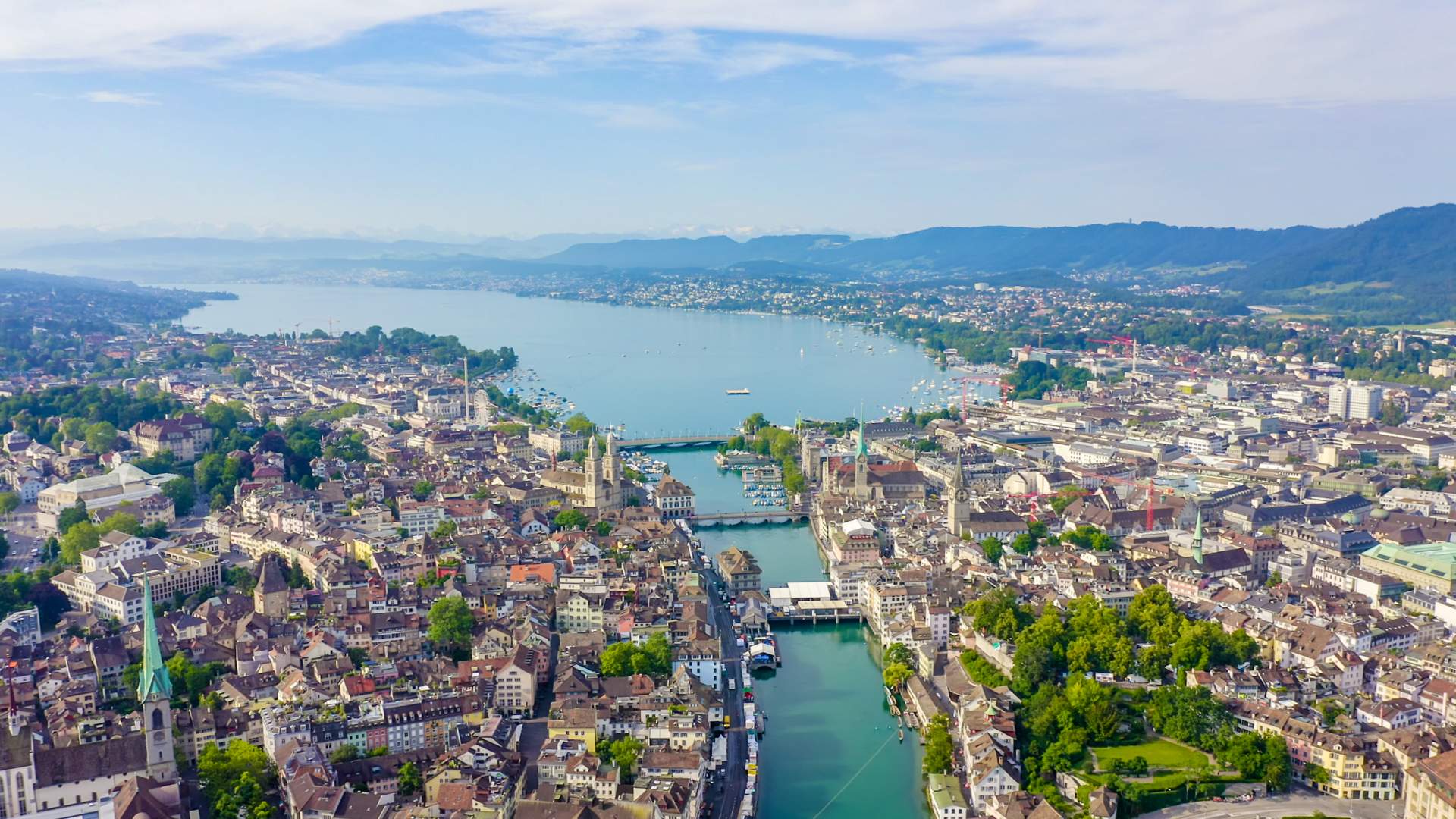 Panoramablick auf Zürich mit der Altstadt, dem Zürcher See und den Alpen im Hintergrund.